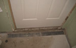 photo of a trench waterproofing basement drain in front of a door to catch water