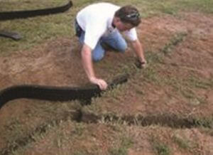 photo of a man installing geo-channel in a yard for yard drainage