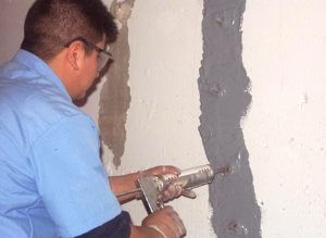 picture of a man applying PolyFoam to fix a basement wall crack